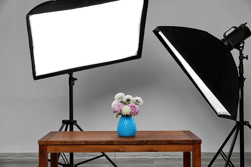 Deux grandes surfaces lumineuses éclairent un petit objet posé sur une table